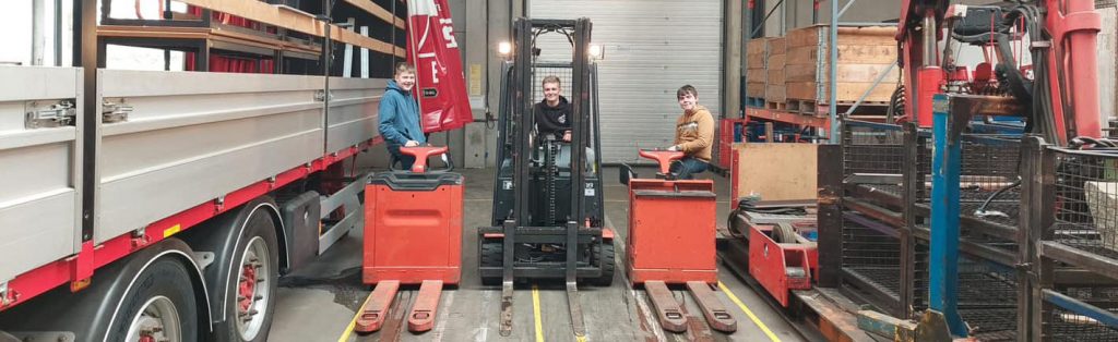 Jongeren met vorkheftrucks in een bedrijf